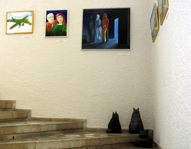 Ant koplyčios laiptų po tapybos ekspozicija sutūpė Skaidrės Račkaitytės moliniai katinai